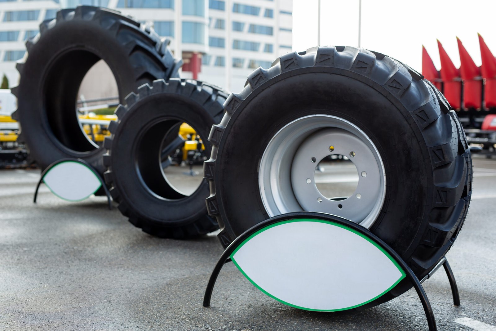 Close up view of three heavy tractor tires and wheels at farming exhibition.